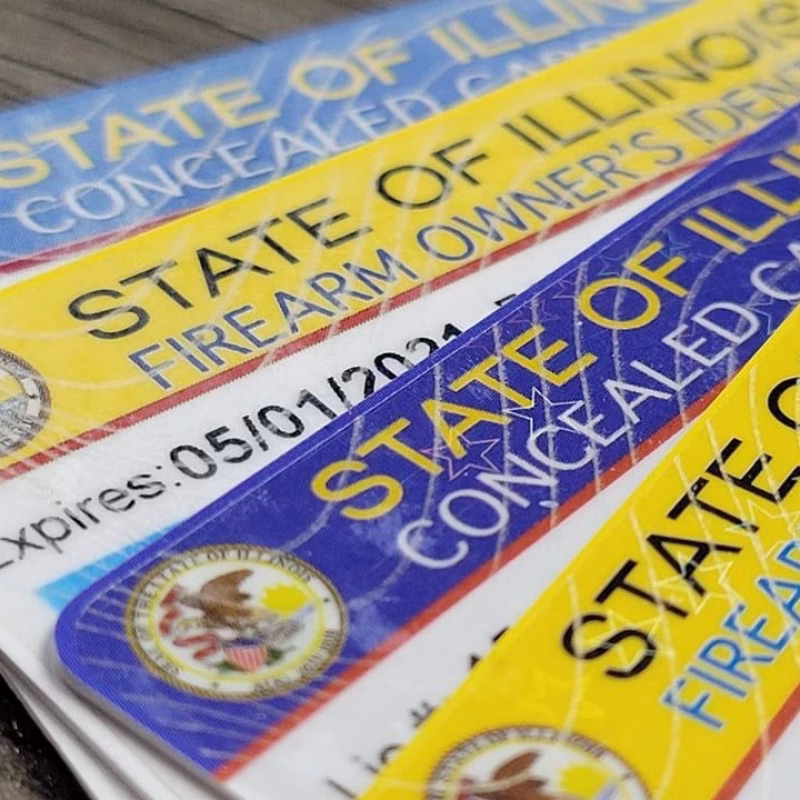 Close-up of several Illinois Concealed Carry licenses and Firearm Owner’s Identification cards, often required for Capacity to Consent Evaluations, showing the state seal, bold text, and expiration dates. The cards are stacked and partially overlapping. - KindestMind